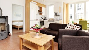 A modern living room with a sofa, a wooden coffee table, and a kitchen in the background. - Holiday Home in Grossenbrode (Grossenbrode)