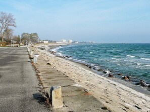 A coastal road with a concrete barrier, a beach, and a distant city skyline. - Holiday Home in Grossenbrode (Grossenbrode)