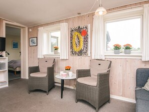 A cozy room with two wicker chairs, a small table, a television, and a window with curtains.