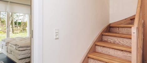 A staircase with wooden steps and a white wall with a power outlet.