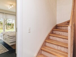 Una escalera con peldaños de madera y una pared blanca con un enchufe.