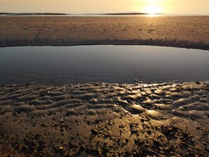 Een strandlandschap met een rustige zee, een zandstrand en een heldere lucht.