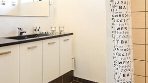 Casa de banho com cortina de chuveiro com palavras relacionadas a água e pia com torneira.