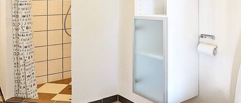 Un baño con ducha, inodoro y toallero.