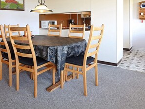 Un comedor con una mesa redonda, sillas de madera y un mantel estampado.