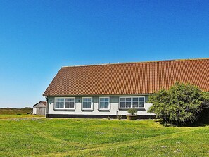 A single-story building with a sloped roof, a front porch, and a small adjacent structure.