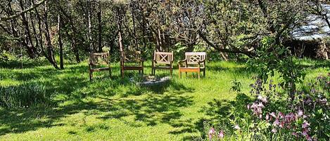 Um jardim com quatro bancos de madeira, diversas plantas e flores.