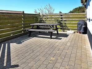 An outdoor patio area with picnic tables and a barbecue grill. - 6 Person Holiday Home in Hvide Sande-by Traum (Hvide Sande)