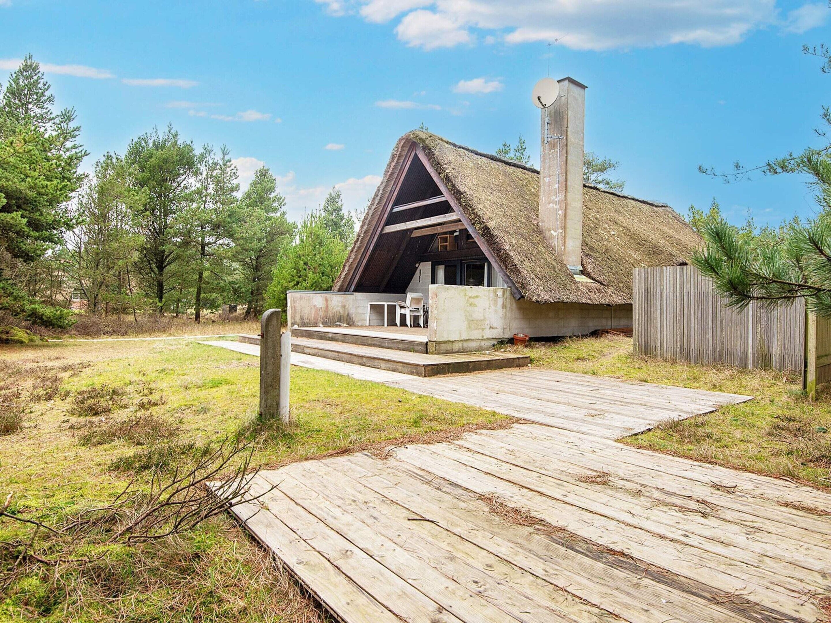 A thatched-roof building with a wooden deck leading to a covered seating area.