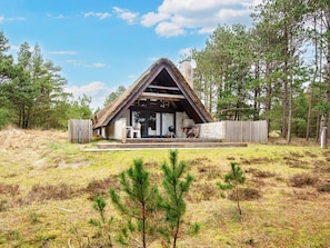 Ett modernt hus med ett sluttande tak, en veranda med sittplatser och utsikt över den omgivande skogen.