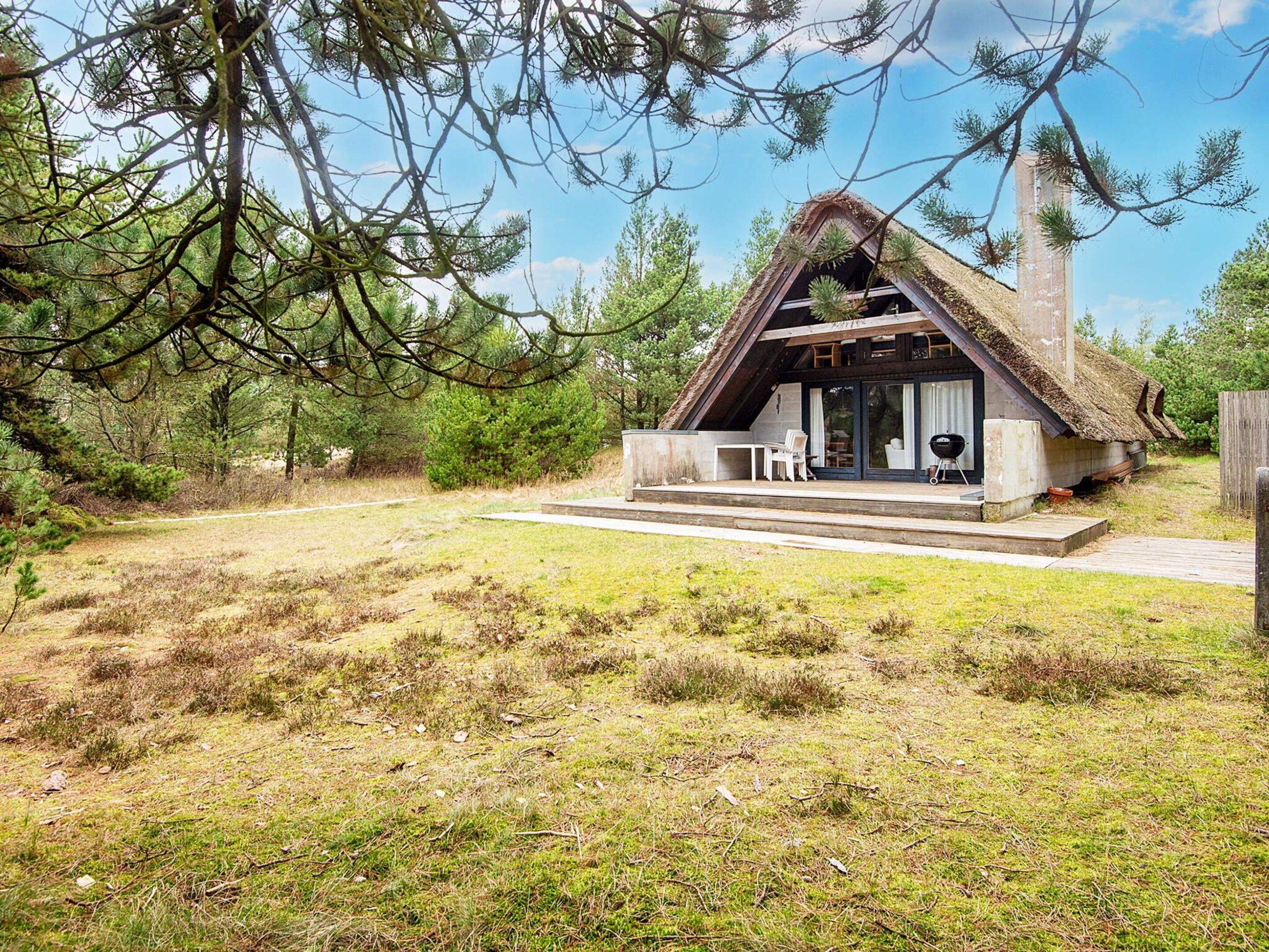 A rustic cabin with a thatched roof, a covered porch, and a small outdoor seating area.