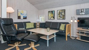 Ein modernes Wohnzimmer mit einer Couch, einem Esstisch und einem Fernseher.