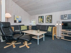 A modern living room with a sofa, a dining table, and a TV. - 4 Star Holiday Home in Ebeltoft (Ebeltoft)