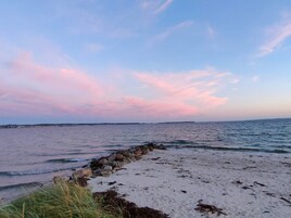 A beach with a rocky breakwater and calm sea.