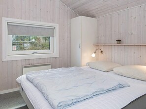 A bedroom with a bed, a window with a view, a bedside lamp, and a radiator. - 4 Star Holiday Home in Ebeltoft (Ebeltoft)