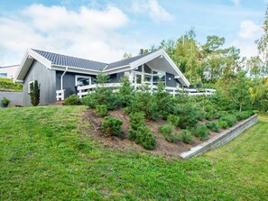 A modern house with a sloped roof, a white fence, and a well-maintained lawn.