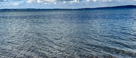 Una playa con agua cristalina y una costa distante.