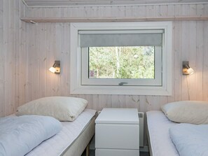 A room with two beds, a window, and two wall-mounted lights.