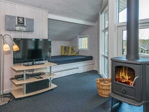 Une pièce confortable avec un lit, une télévision et un poêle à bois.