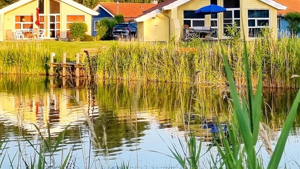 Fileira de casas com um lago ao primeiro plano, refletindo os edifícios.