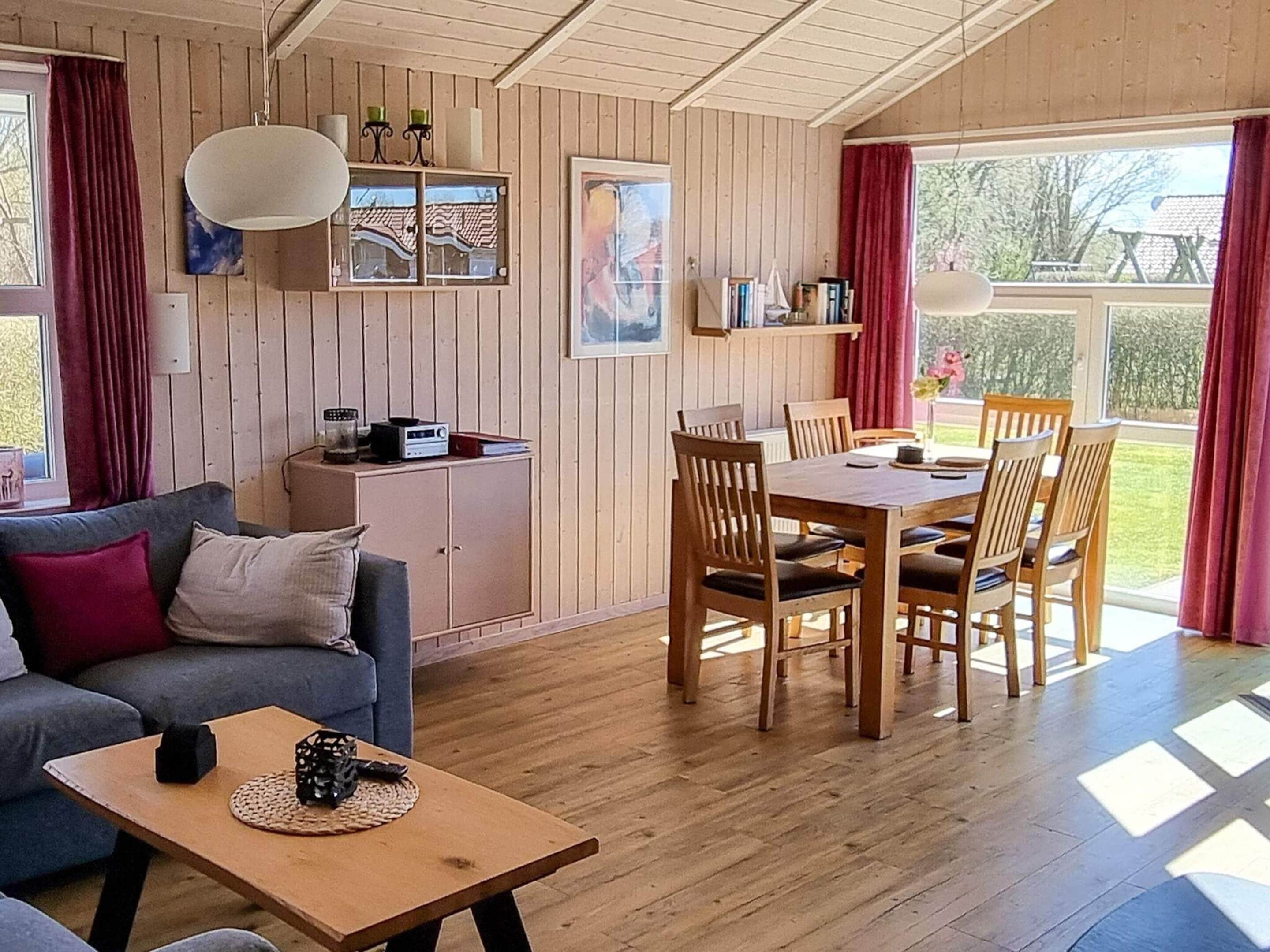 A cozy room with a sofa, a dining table with chairs, a kitchen area, and a view of the outdoors.