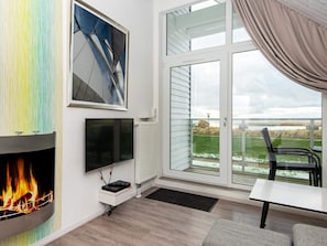Una sala de estar moderna con chimenea, televisor de pantalla plana y un ventanal con vistas a un jardín.
