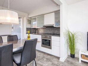 A modern kitchen with white cabinets, a black countertop, and a stainless steel oven.