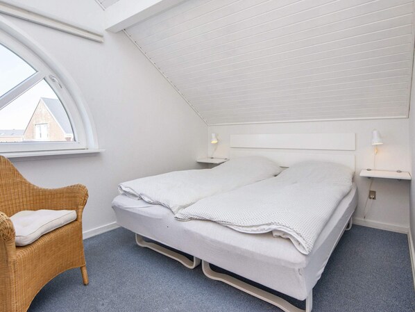 A bedroom with a bunk bed, a window, a chair, and bedside lamps.