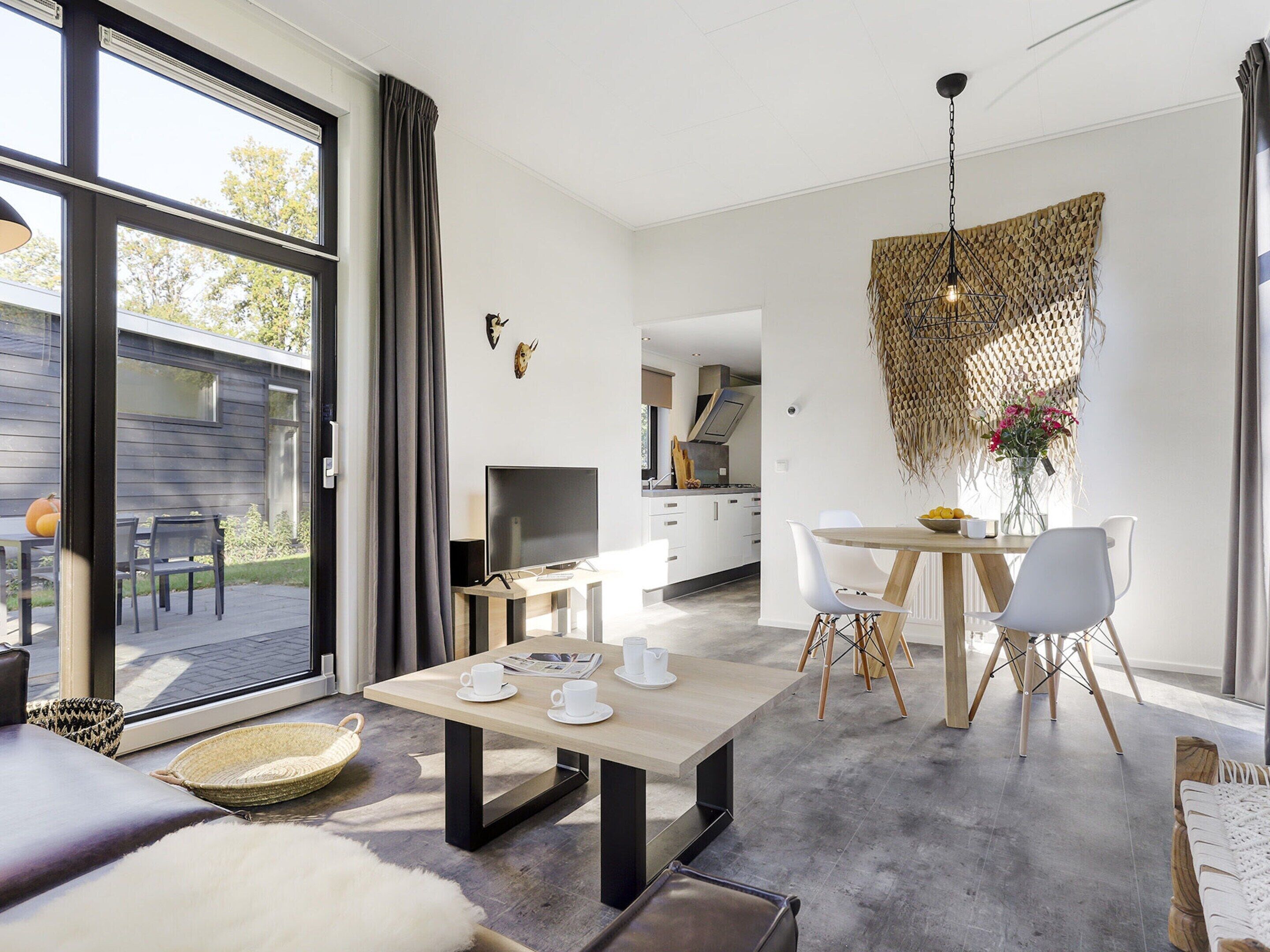 A modern interior with a dining area, kitchen, and a large sliding glass door leading to an outdoor space.