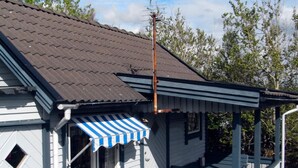 Een gebouw met een blauw-wit gestreepte luifel, een bord met de tekst 'Fiskestugam' en een metalen trap die naar een veranda leidt.