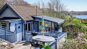 Een blauw huis met een terras, een barbecue en uitzicht op zee.