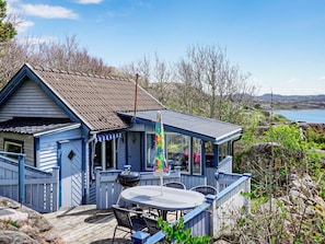 Een blauw huis met een terras, een barbecue en uitzicht op zee.
