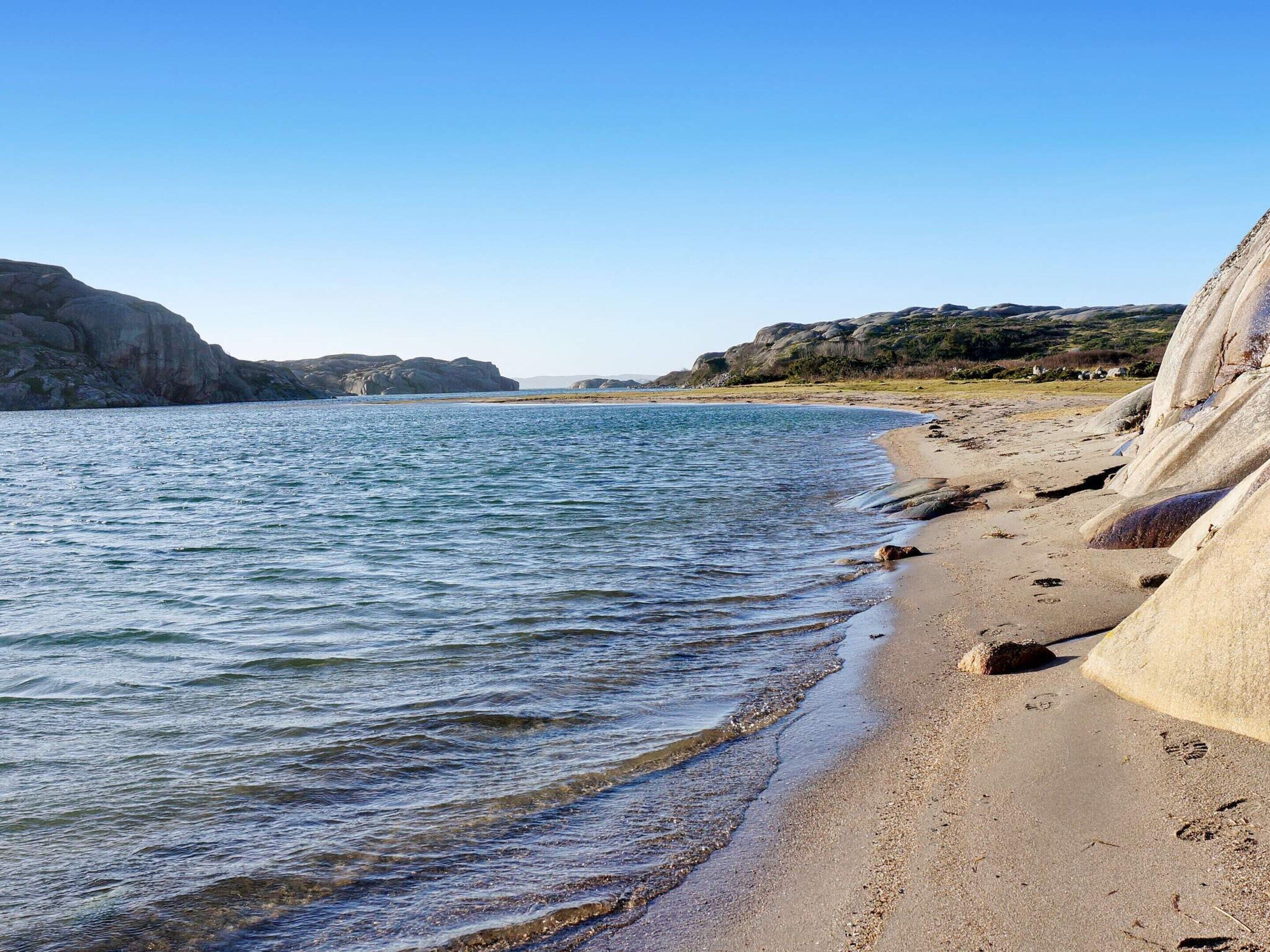 Une plage côtière avec une eau claire, des falaises rocheuses et une rive sablonneuse.