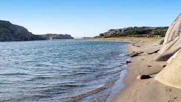 Uma praia costeira com águas cristalinas, falésias rochosas e uma orla arenosa.