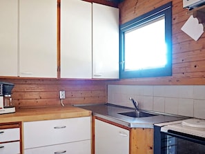 Eine kleine Küche mit Holzschränken, einem Spülbecken und einem Fenster.