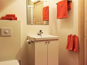 A bathroom with a sink, mirror, and two towels hanging on the wall. - Holiday Home in tau (Strand)