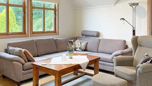 A cozy living room with a sectional sofa, a wooden coffee table, and a floor lamp. - Holiday Home in tau (Strand)