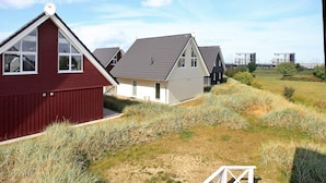 A row of modern houses with sloped roofs and satellite dishes, set in a grassy area with a clear sky. - Holiday Home in Wendtorf (Wendtorf)