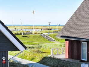 A coastal property with a view of the sea, a wooden building, and a pathway leading to a bench. - Holiday Home in Wendtorf (Wendtorf)