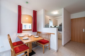 A dining area with a wooden table, red cushioned chairs, a bench, and a hanging lamp. - Apartment in Obertraun Near Krippenstein Ski Area (Obertraun)