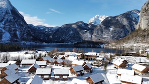 A snow-covered village with wooden houses, a lake, and mountains in the background. - Apartment in Obertraun Near Krippenstein Ski Area (Obertraun)
