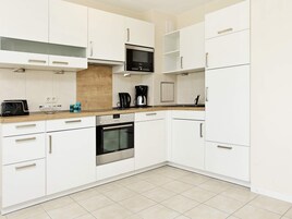 A modern kitchen with white cabinetry, a built-in oven, a microwave, and a coffee maker.