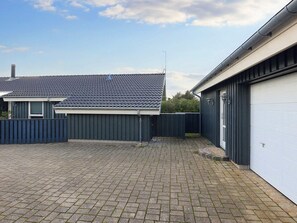 A residential property with a paved driveway, a detached garage, and a fenced backyard. - 5 Star Holiday Home in Lokken (Lokken)