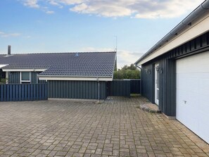 A residential property with a paved driveway, a detached garage, and a fenced backyard.