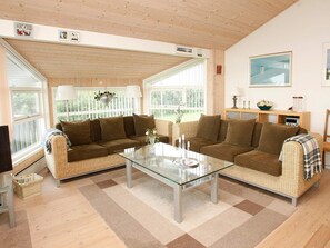 A living room with a glass coffee table, two sofas, a television, and a bookshelf.