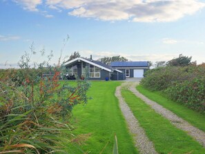 A modern house with a sloped roof, a garage, and a well-maintained lawn with a gravel path.
