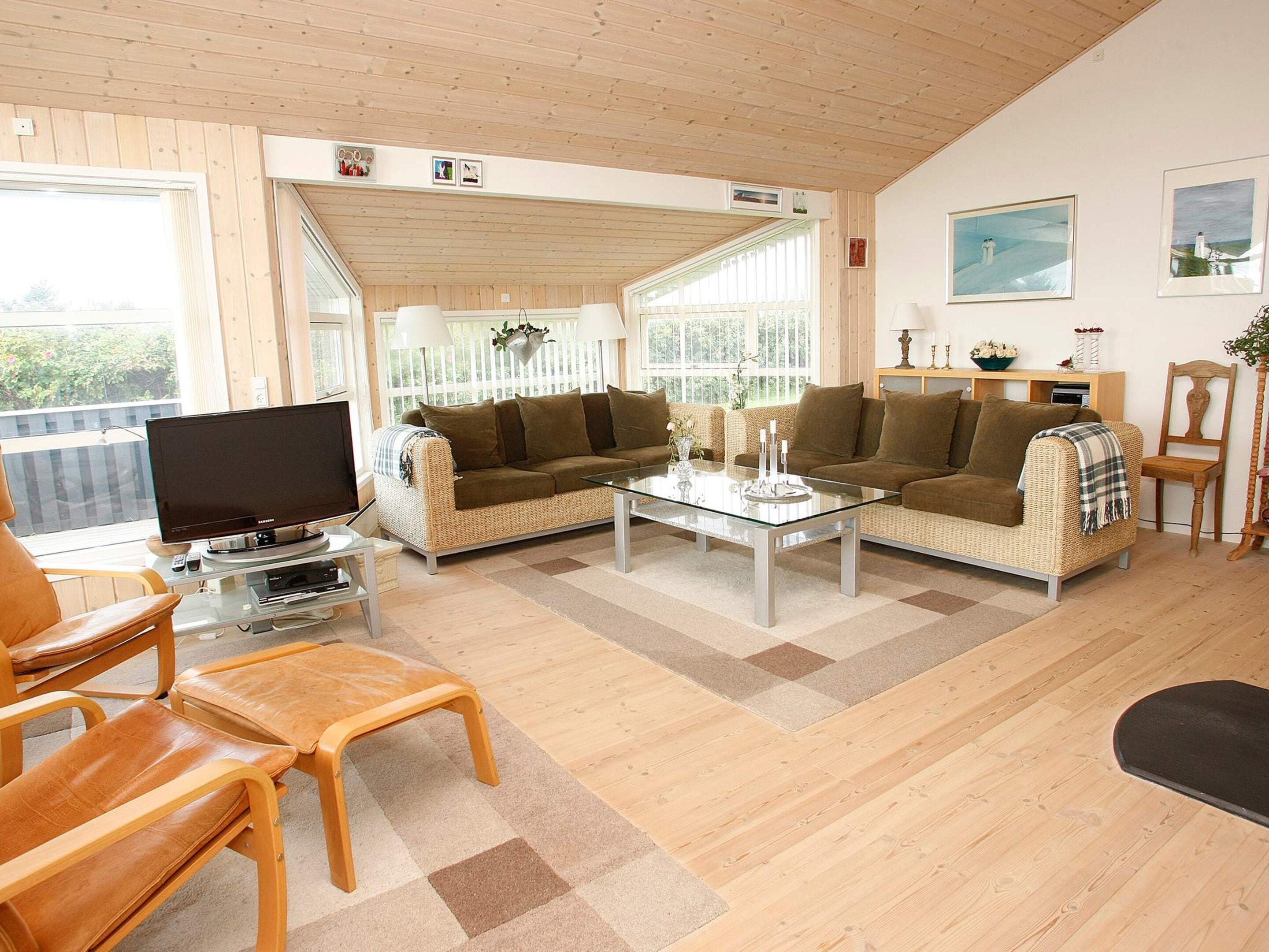 A furnished living room with a sofa, chairs, a coffee table, and a television.