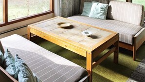A cozy room with a sofa, a bench, and a wooden table with a bowl and a plate. - Cozy Holiday Home in Nexo near Dueodde Beach (Nexø)