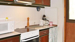 A compact kitchen with a microwave, stove, and coffee maker. - Cozy Holiday Home in Nexo near Dueodde Beach (Nexø)