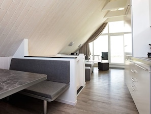 A modern loft-style room with a dining area, kitchenette, and seating space. - Holiday Home in Wendtorf (Wendtorf)